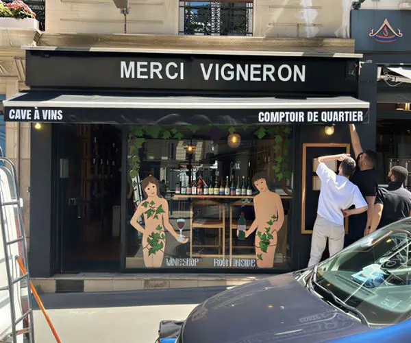 Ancienne devanture commerciale à Paris 5ème avec superposition de coffrages et grille de protection usagée avant intervention
